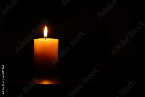 One burning candle on black background, space for text