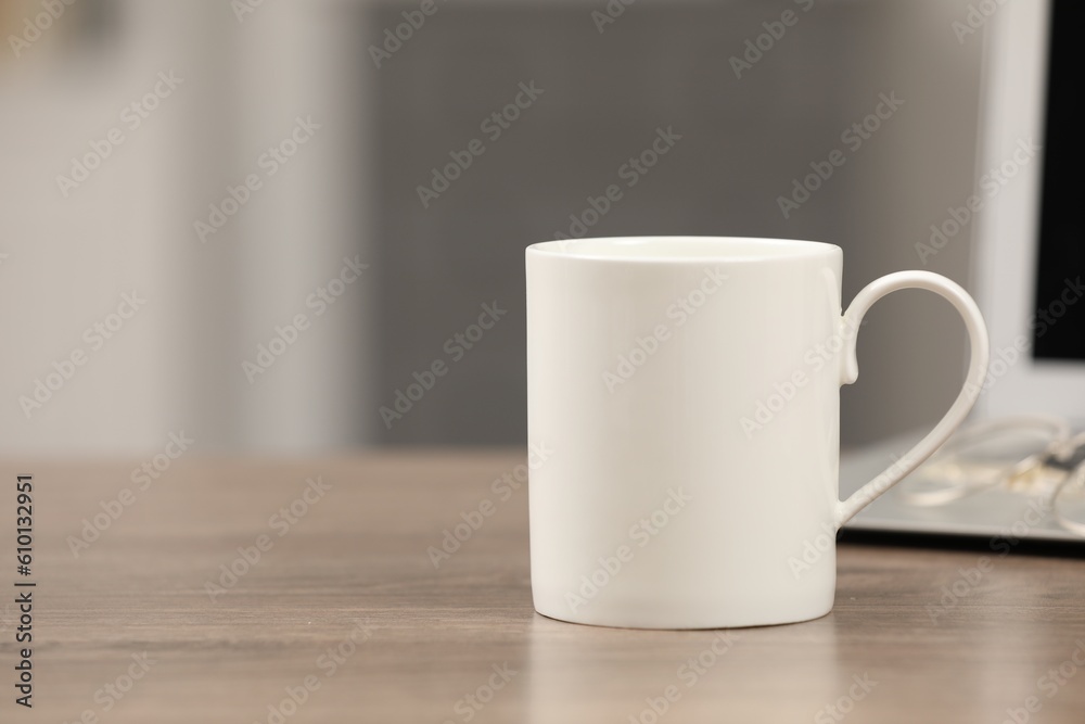 White ceramic mug and laptop on wooden table at workplace. Space for text White ceramic mug and laptop on wooden table at workplace. Space for text