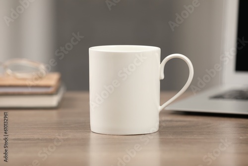 White ceramic mug on wooden table at workplace