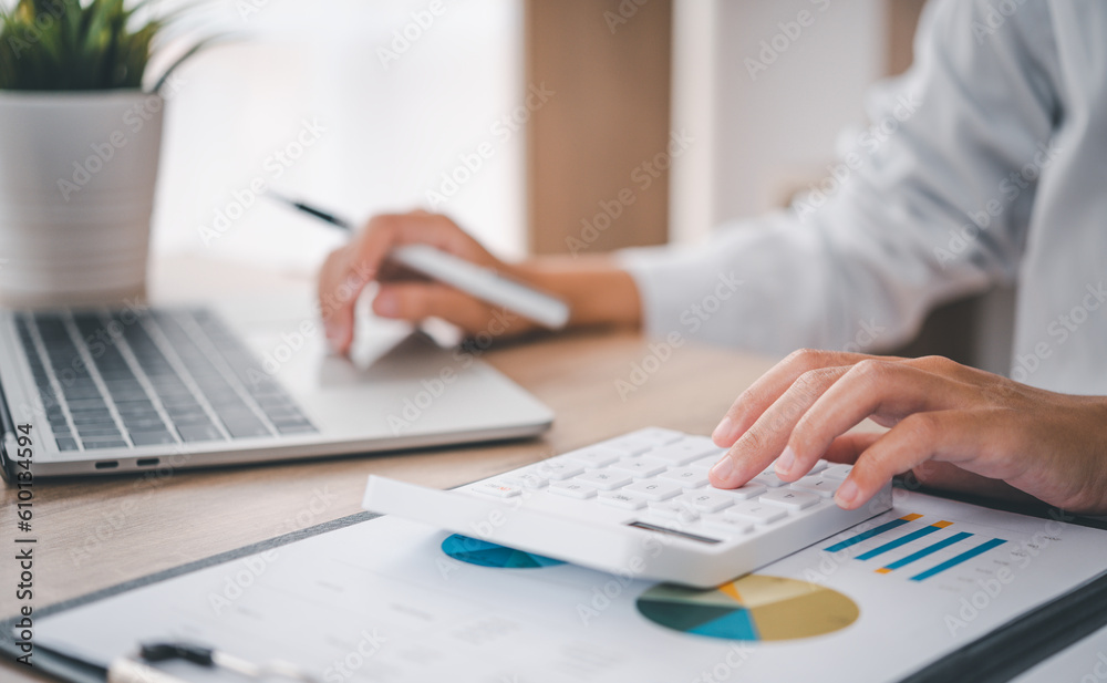 close up The business person is sitting on a calculator with a graph in the office of finance accounting concept close up The business person is sitting on a calculator with a graph in the office of finance accounting concept