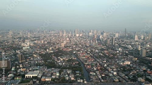 Stunning aerial view of the Bangkok city skyline with towering skyscrapers in the distance, and the scenic Chao Phraya River canal just before sunset. photo