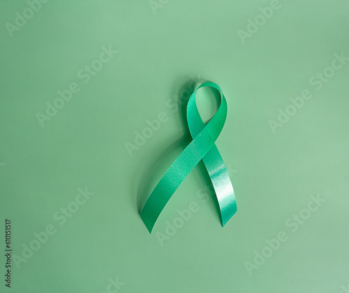 Green ribbon a symbol of the global women's breast cancer campaign. oncological disease prevention and female healthcare. shot isolated on green background