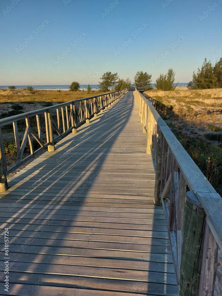 Wooden walkway leading to the beach at sunset in summer