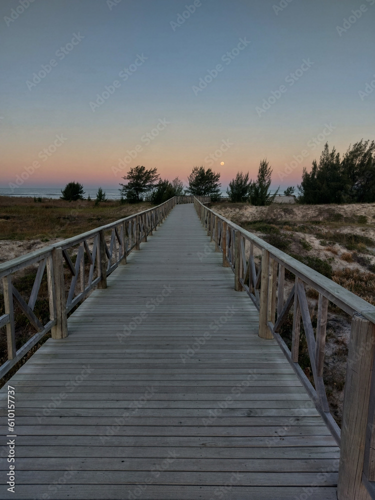 Wooden walkway leading to the beach at sunset in summer