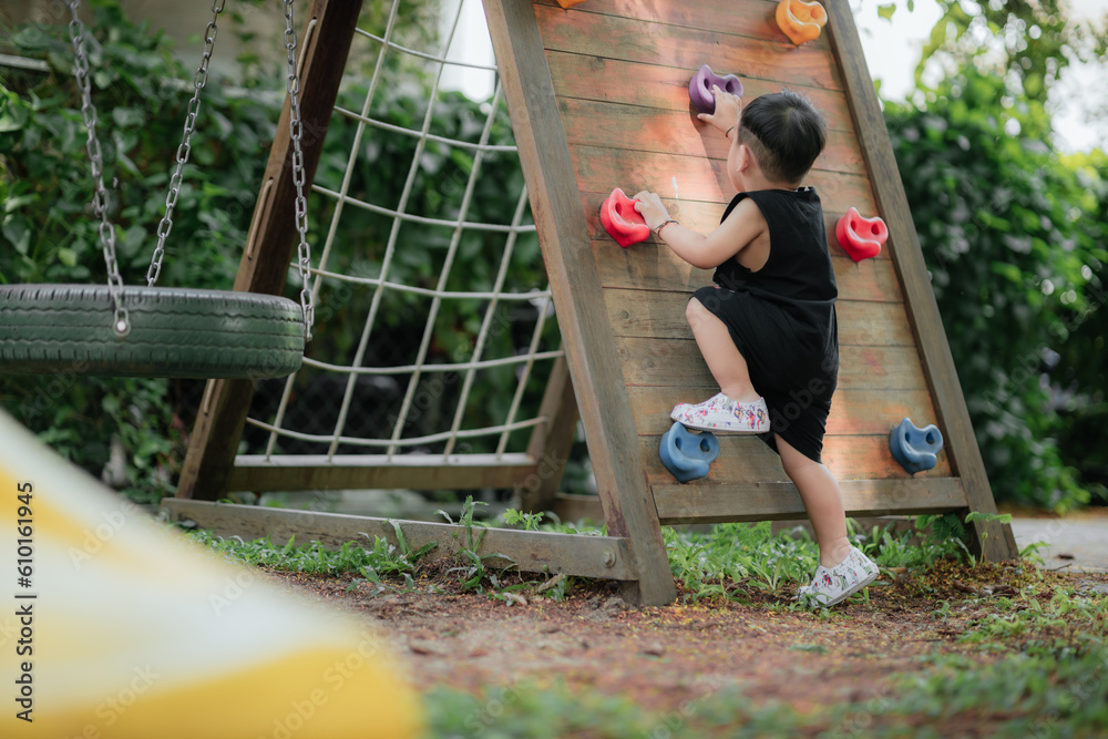 Fototapeta premium Asian little boy playing in the playground outdoor. Kids play on school or kindergarten yard. Healthy summer activity for children.