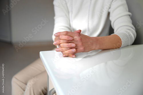 Unhappy woman crossing hands while sitting near the desk in the office. A pensive girl at a doctor's consultation. Depressed frustrated young girl 