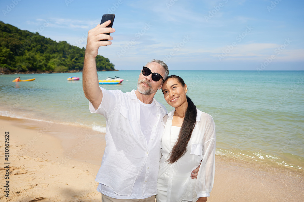 couple taking a selfie by smartphone on the beach