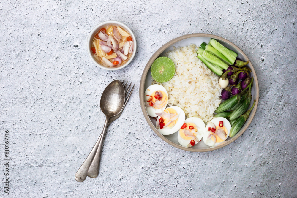 Healthy food brown rice dish with boiled eggs chili line has cucumber eggplant vegetable in bowl isolated on white slate table. Healthy food brown rice dish with boiled eggs chili line has cucumber eggplant vegetable in bowl isolated on white slate table.