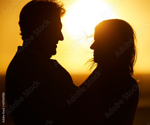 Silhouette, couple and love at sunset on beach for vacation, holiday or adventure outdoor in nature. Romantic man and woman in marriage with sky background for care, shadow art and travel freedom