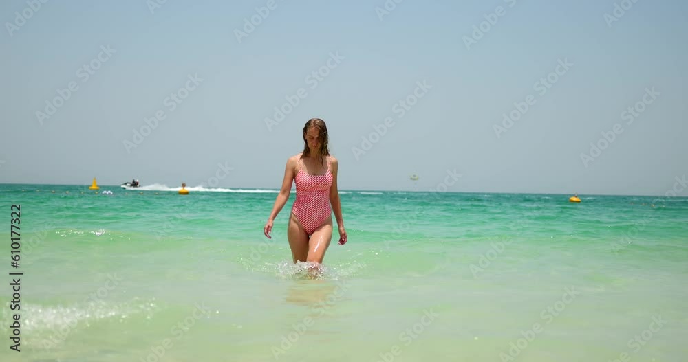 Tourist woman in swimsuit leave the sea after swimming on Jumeirah beach. Tourist woman in swimsuit leave the sea after swimming on Jumeirah beach.