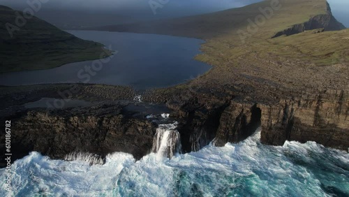 fantastic aerial shot in orbit over the lake SØRVÁGSVATN and the waterfall that is located there. In the Faroe Islands and during sunset. photo