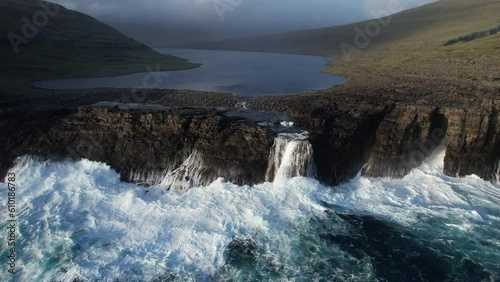 Fantastic aerial shot in close-up of the SØRVÁGSVATN lake and the waterfall that is located there. Incredible waves break against the cliffs. In the Faroe Islands and during sunset. photo