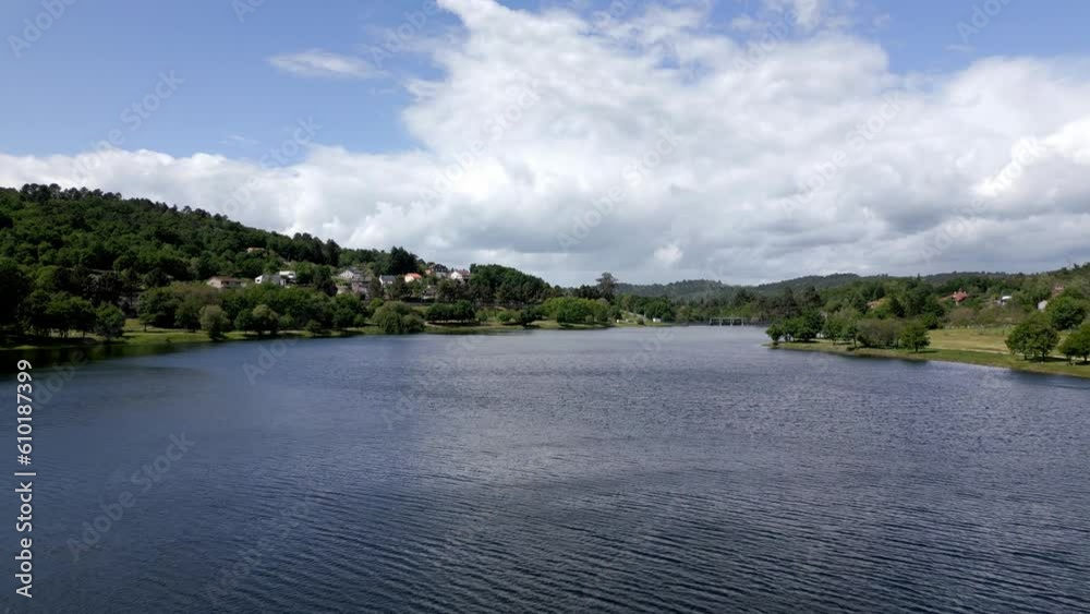 Rio Lonia reservoir above water and homes on forested hillside, aerial dolly