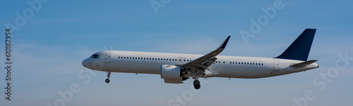 Side view of an airplane landing against a blue sky. Widescreen. 