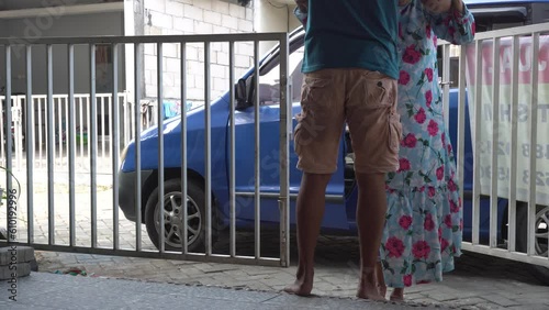 a man helping to support his elderly mother walking slowly and stuttering out of the car into the house photo