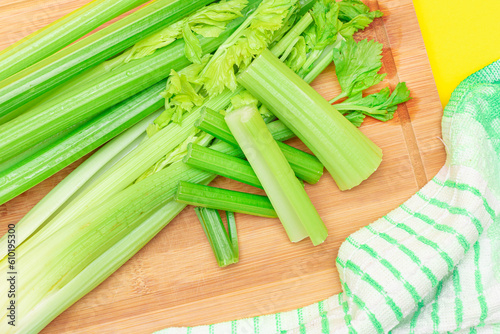Fresh Celery Stem and Chopped Celery Sticks on Wooden Cutting Board. Vegan and Vegetarian Culture. Raw Food. Healthy Diet with Negative Calorie Content. Slimming Food