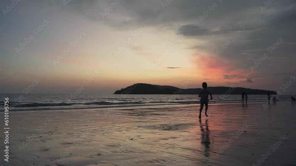 Little boy is running along a sand beach at sunset Little boy is running along a sand beach at sunset