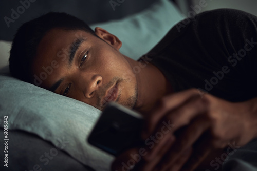 Night, bed and tired man with phone, internet scroll and social media post or texting, insomnia in home. Wake up, browse and exhausted male in dark bedroom with cellphone, mobile game or digital app.