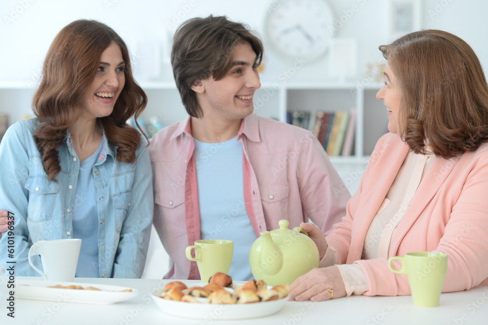 family of three spending time together at dinner table with cookies and tea family of three spending time together at dinner table with cookies and tea
