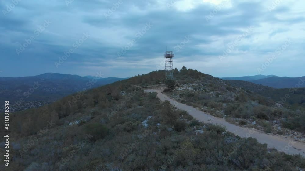 Experience the breathtaking view of a hilltop watchtower captured in an aerial drone shot during a dramatic overcast dawn Experience the breathtaking view of a hilltop watchtower captured in an aerial drone shot during a dramatic overcast dawn