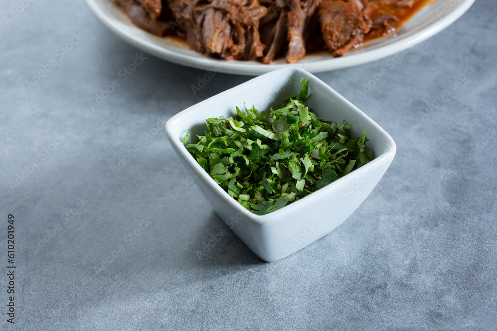 A view of a condiment cup of chopped cilantro. A view of a condiment cup of chopped cilantro.