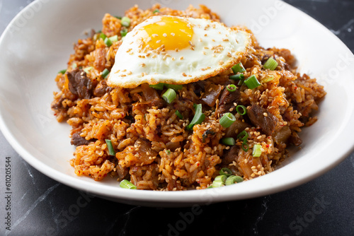 A view of a plate of kimchi fried rice, featuring a fried egg.