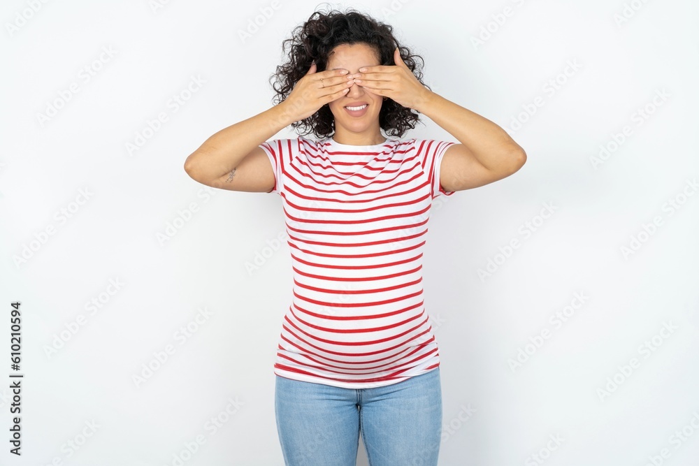 young pregnant woman wearing striped t-shirt over white background covering eyes with hands smiling cheerful and funny. Blind concept. young pregnant woman wearing striped t-shirt over white background covering eyes with hands smiling cheerful and funny. Blind concept.