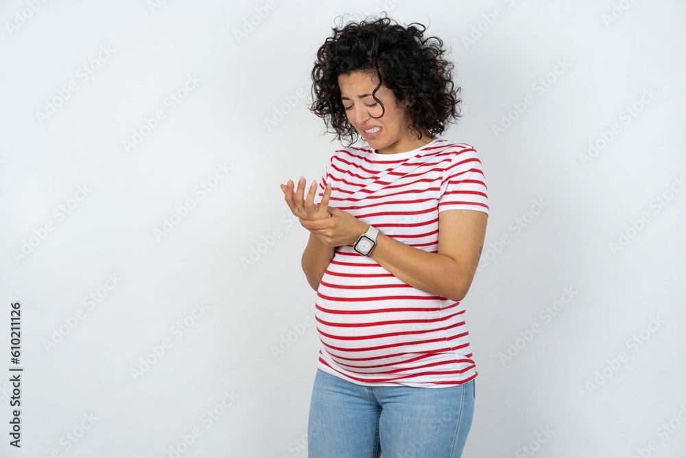 young pregnant woman wearing striped t-shirt over white background Suffering pain on hands and fingers, arthritis inflammation young pregnant woman wearing striped t-shirt over white background Suffering pain on hands and fingers, arthritis inflammation