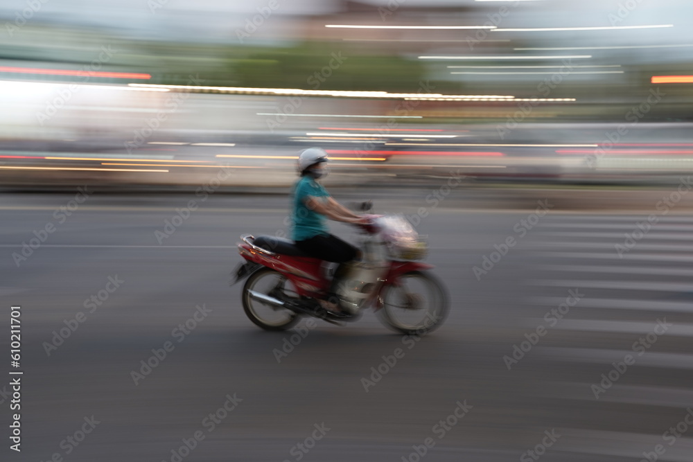Person on scooter motorbike speeding through the city street - motion blur shot 