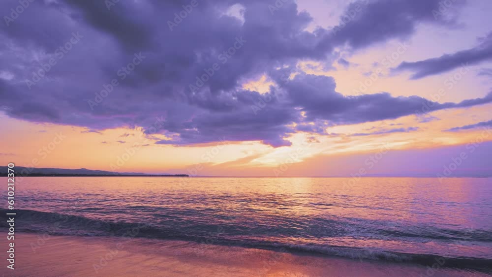 Lilac landscape of the morning sky with a sun glow in thick clouds over the ocean. Calm sea waves on a sandy beach at dawn. Exotic nature view. Inspirational seascape. Twilight on the beach. Lilac landscape of the morning sky with a sun glow in thick clouds over the ocean. Calm sea waves on a sandy beach at dawn. Exotic nature view. Inspirational seascape. Twilight on the beach.