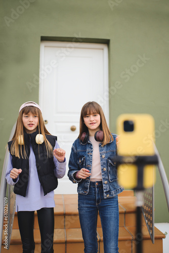 Teenage sisters filming together dancing on the front porch as they make videos for social media  hip hop stories  hip popular dance  young people at home creating content.