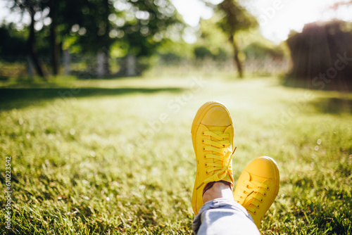 Fototapeta Naklejka Na Ścianę i Meble -  Youth sneakers on girl legs on grass during sunny summer day