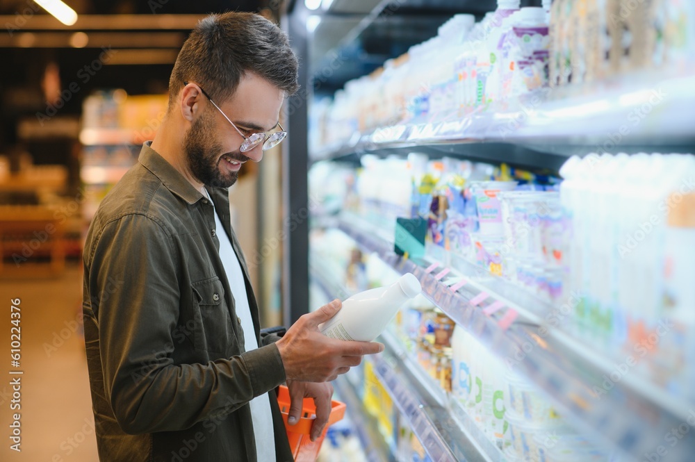 Handsome man buying some healthy food and drink in modern supermarket