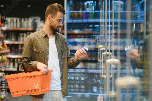 Cuadro en lienzo Man with a beard buys a beer in the alcohol department of a supermarket