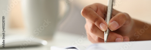 Closeup cropped hands of young woman writing day plan in notebook at workplace at computer. Concept of work and study at home concept