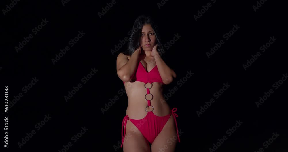 At nightfall, a captivating young woman exudes allure as she confidently showcases her beauty in a red bikini At nightfall, a captivating young woman exudes allure as she confidently showcases her beauty in a red bikini