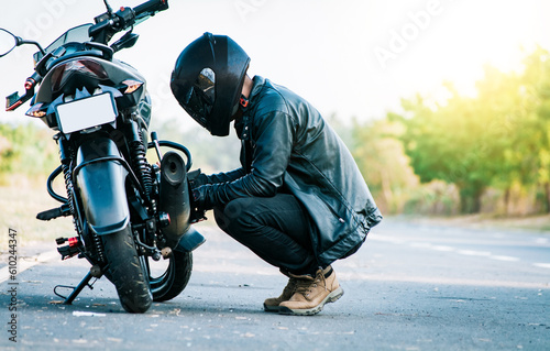 Biker repairing motorcycle on the road. Motocyclist fixing the motorcycle on the road, Man checking his motorcycle on the road © IHERPHOTO