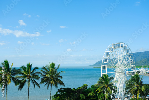 Blue skies and the clear turquoise waters of the Coral Sea framed by palm trees at Cairns Esplanade — Far North Queensland, Australia