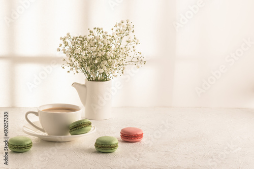 Coffee, macarons and a bouquet of gypsophila on a white table. Women's desk. Cozy breakfast. photo