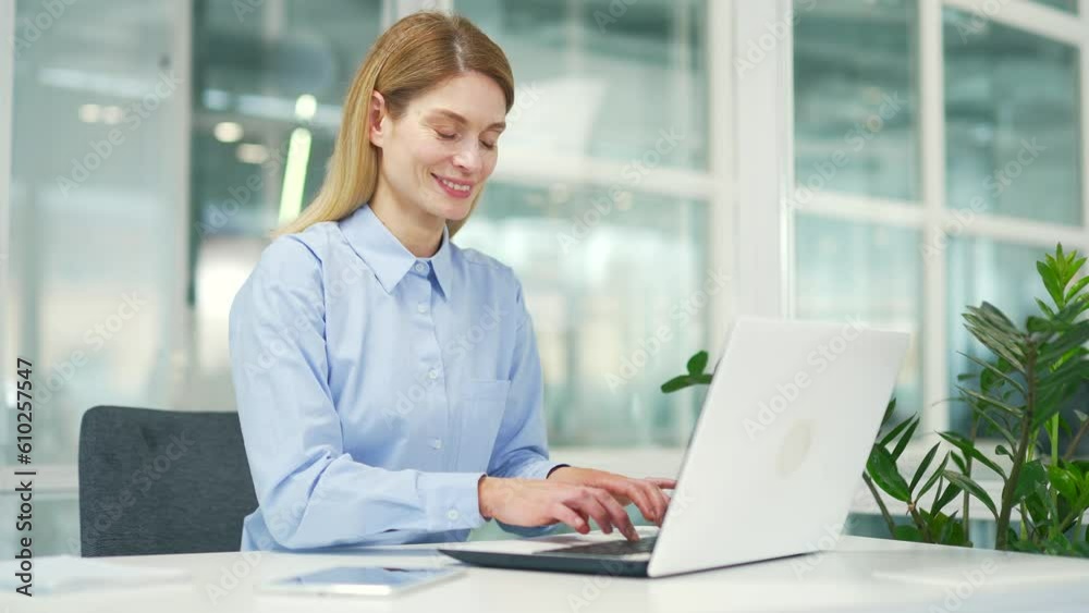 Mature businesswoman working using typing on laptop while sitting at desk at workplace in modern office. Smiling female employee working on a project on the computer, texting a client, chatting online Mature businesswoman working using typing on laptop while sitting at desk at workplace in modern office. Smiling female employee working on a project on the computer, texting a client, chatting online