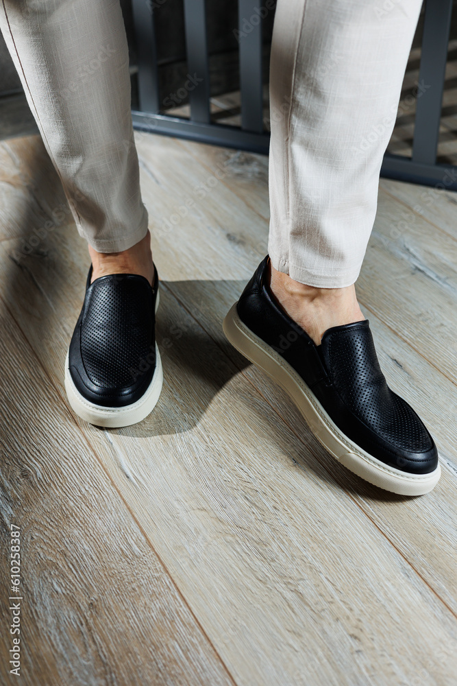 Male legs in leather shoes. Comfortable men's black shoes without laces. Casual men's moccasins
