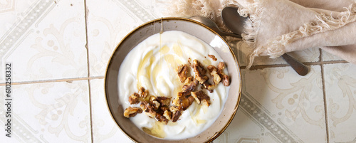 a bowl of greek yogurt with walnuts and honey on a light table