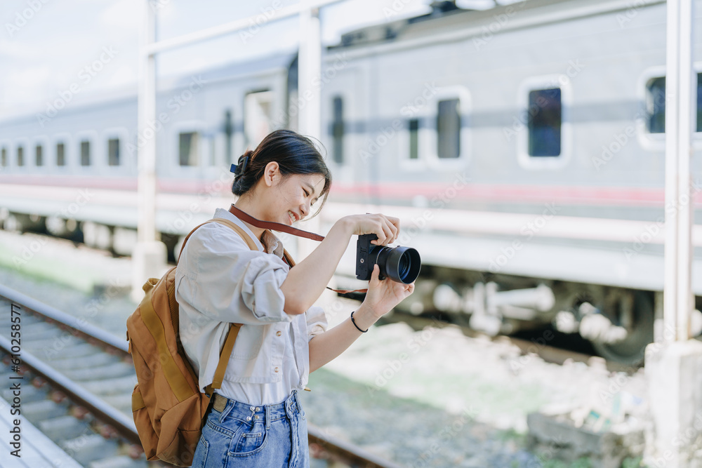 Asian teenage girl traveling using a camera take a photo to capture memories while waiting for a train at the station. Asian teenage girl traveling using a camera take a photo to capture memories while waiting for a train at the station.