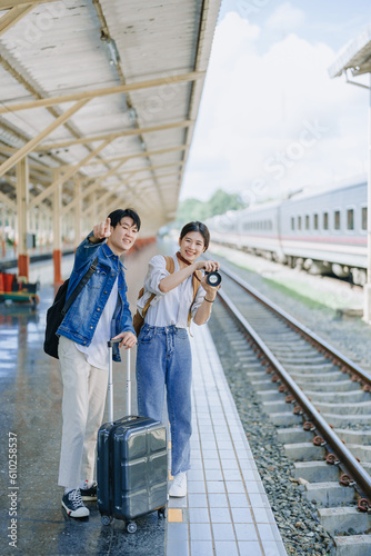 Young couple traveling using a camera to capture memories while waiting for the train at the station.travel concepts.