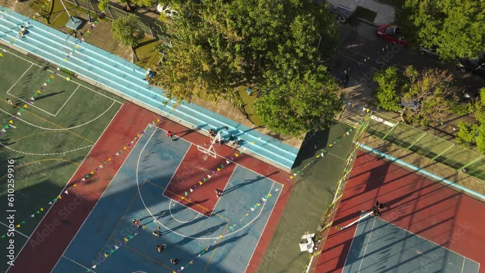 Group of students playing basketball on amateur court during festival - aerial straight down orbiting Group of students playing basketball on amateur court during festival - aerial straight down orbiting