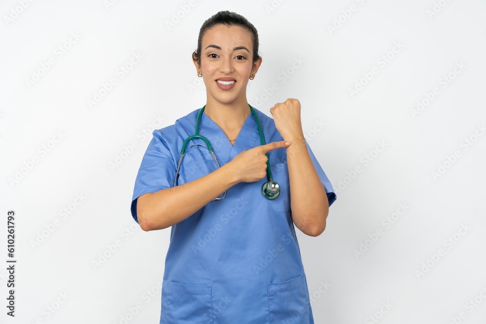 Beautiful doctor woman standing over white studio background In hurry pointing to wrist watch, impatience, looking at the camera with relaxed expression Beautiful doctor woman standing over white studio background In hurry pointing to wrist watch, impatience, looking at the camera with relaxed expression
