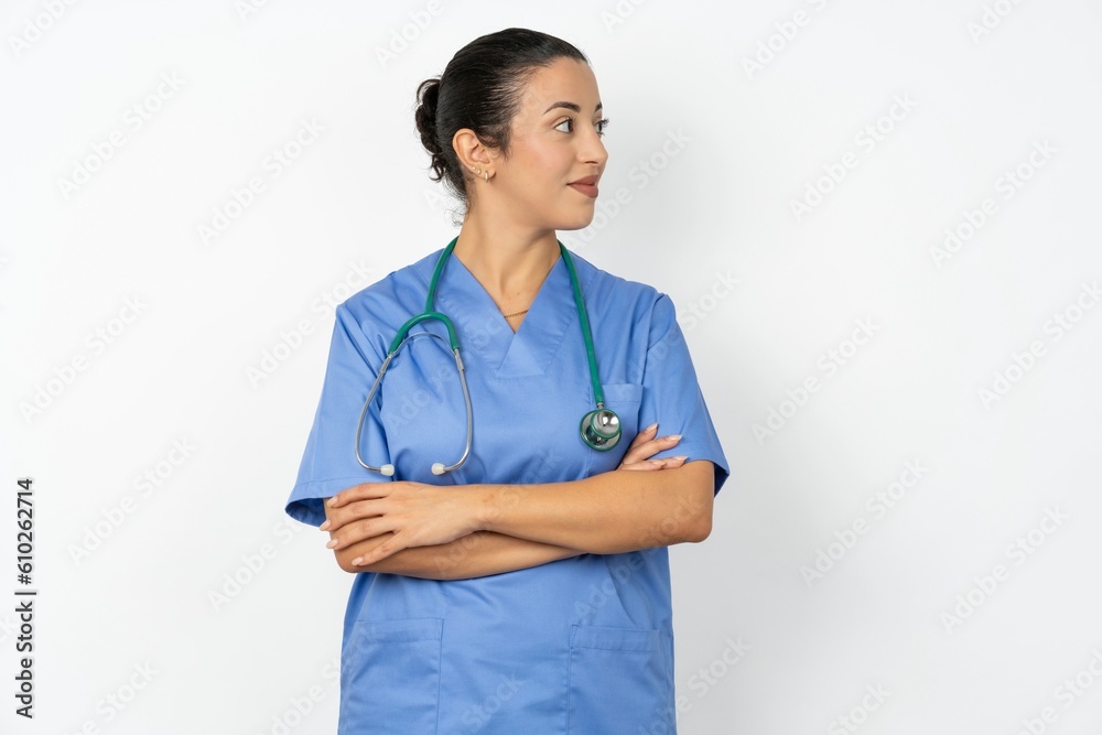 Charming thoughtful Beautiful doctor woman standing over white studio background stands with arms folded concentrated somewhere with pensive expression thinks what to do Charming thoughtful Beautiful doctor woman standing over white studio background stands with arms folded concentrated somewhere with pensive expression thinks what to do