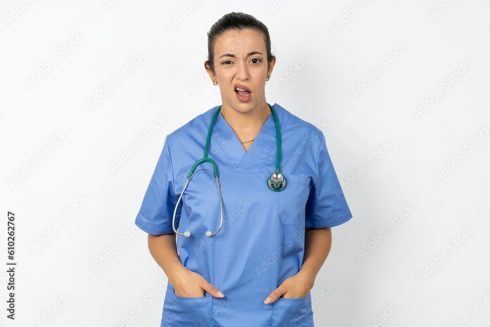 Portrait of dissatisfied Beautiful doctor woman standing over white studio background smirks face, purses lips and looks with annoyance at camera, discontent hearing something unpleasant Portrait of dissatisfied Beautiful doctor woman standing over white studio background smirks face, purses lips and looks with annoyance at camera, discontent hearing something unpleasant