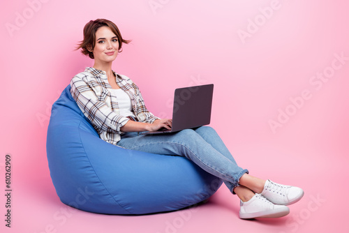 Full body portrait of nice positive lady sit cozy bag use netbook isolated on pink color background