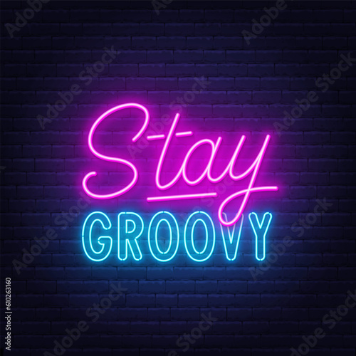 Stay Groovy neon lettering on brick wall background.